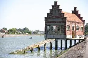 Le Musée du Sauvetage de Grand-Fort-Philippe, un bâtiment en briques rouges sur pilotis avec des pignons à pas de moineau et une passerelle en bois, situé au bord du chenal de l'Aa.